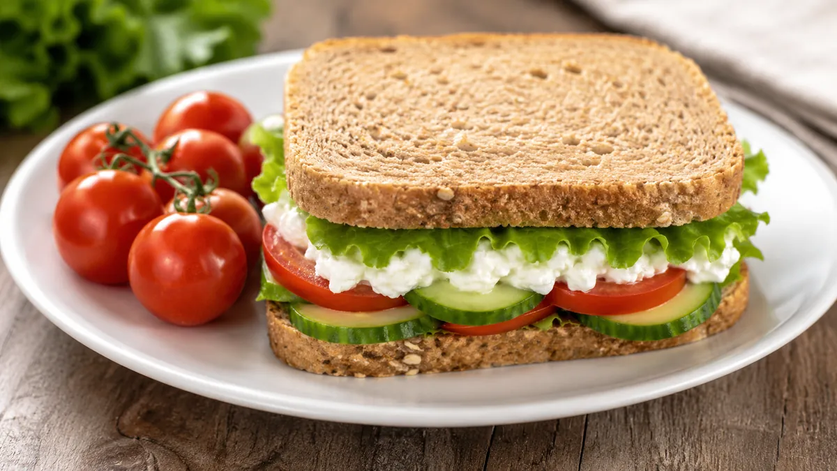 ساندويتش خبز قمح كامل محشو جبنة قريش وخس وطماطم وخيار مع طماطم كرزية